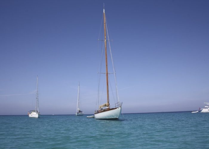 Classic sailing yacht Yanira anchored off beach